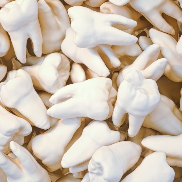 Eine Ansammlung von weißen Zahnmodellen auf einem hellen Hintergrund.